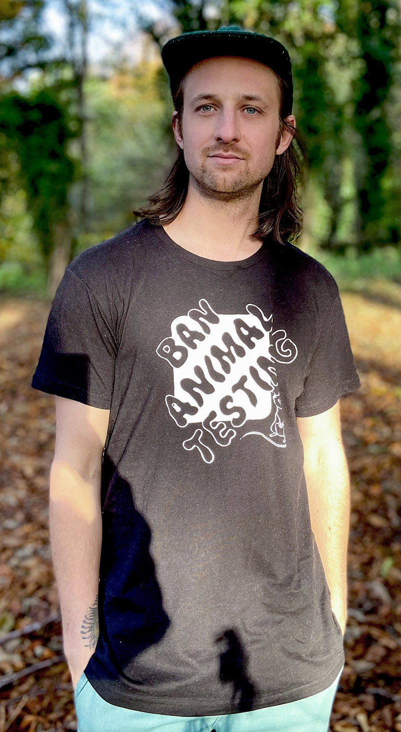 Supporter looking to the side wearing a black tshirt displaying the words Ban Animal Testing in black, with a white block background and small white mouse looking up