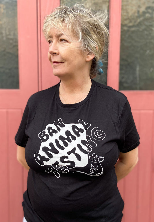 Supporter looking to the side wearing a black tshirt displaying the words Ban Animal Testing in black, with a white block background and small white mouse looking up